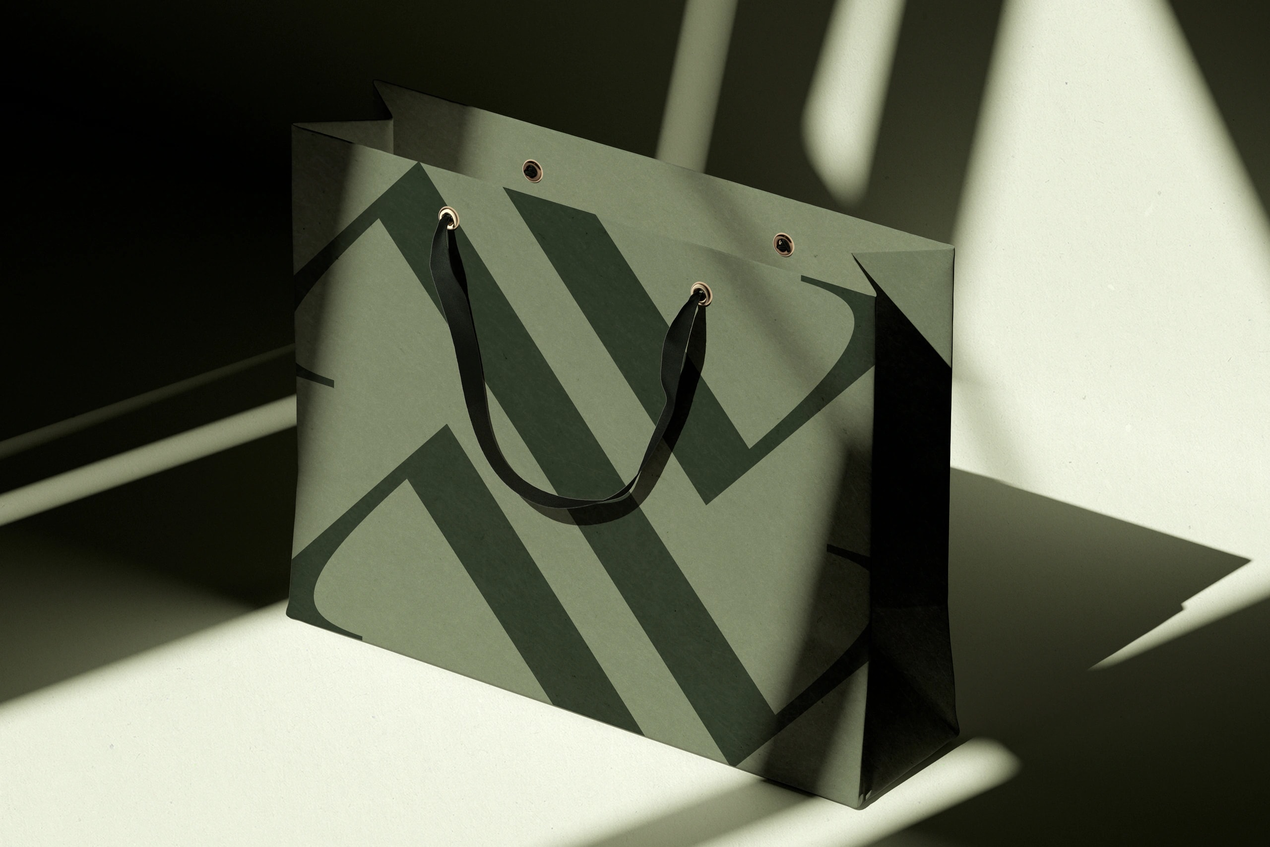 Grüne Papiertüte mit Markenlogo als Branding- und Verpackungsdesign im Schattenlicht